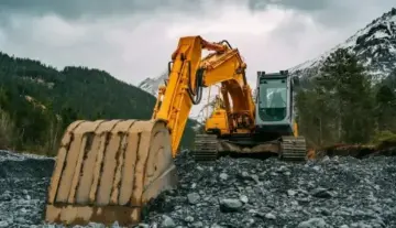  Ein Traktor mit Anhänger steht auf einem grünen Hügel, umgeben von saftigem Gras und klarem Himmel.